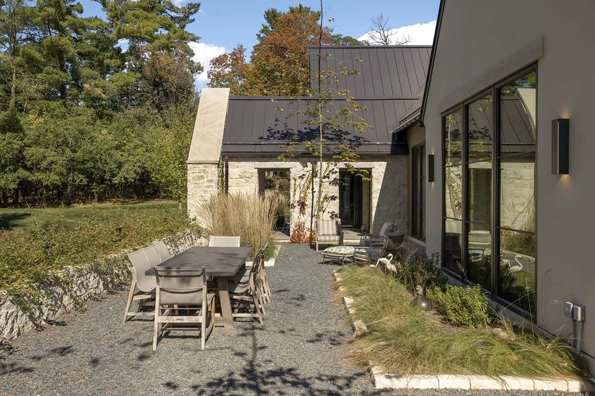 Gravel patio with dining table and stone chimney backdrop