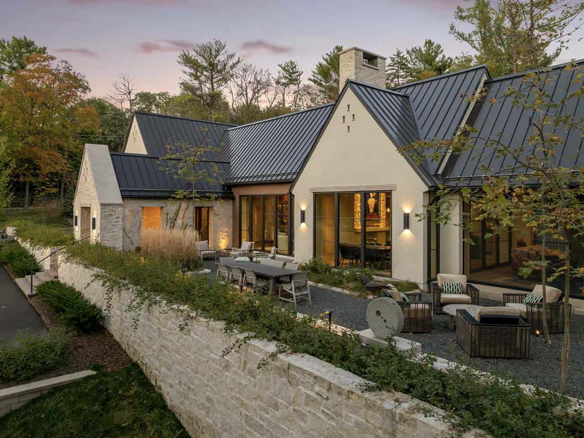 Dusk exterior with stone chimney and illuminated dining room