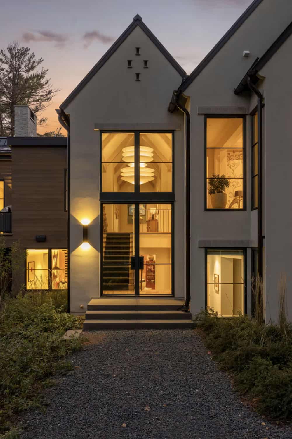 Two story glass entry illuminated at dusk with staircase view