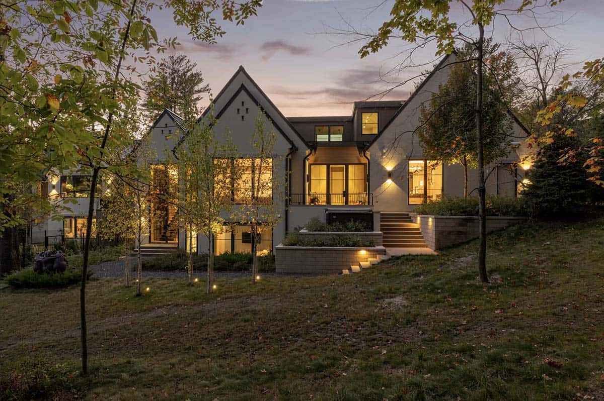 Dusk exterior with lit windows framed by birch trees