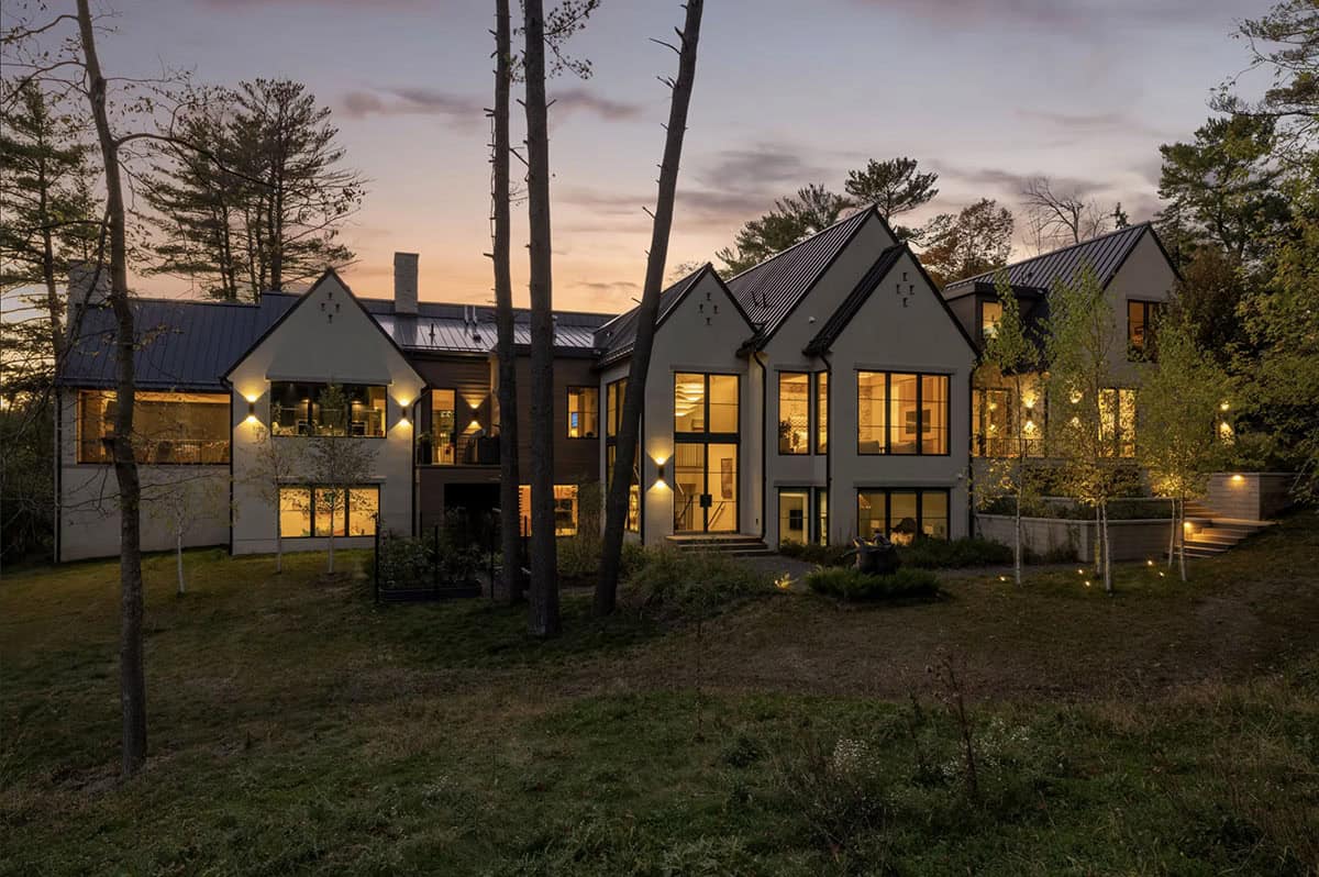 Wide dusk view of gabled roofline glowing from within