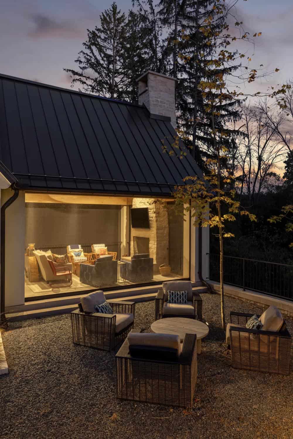 Dusk view of screened porch with stone fireplace and seating