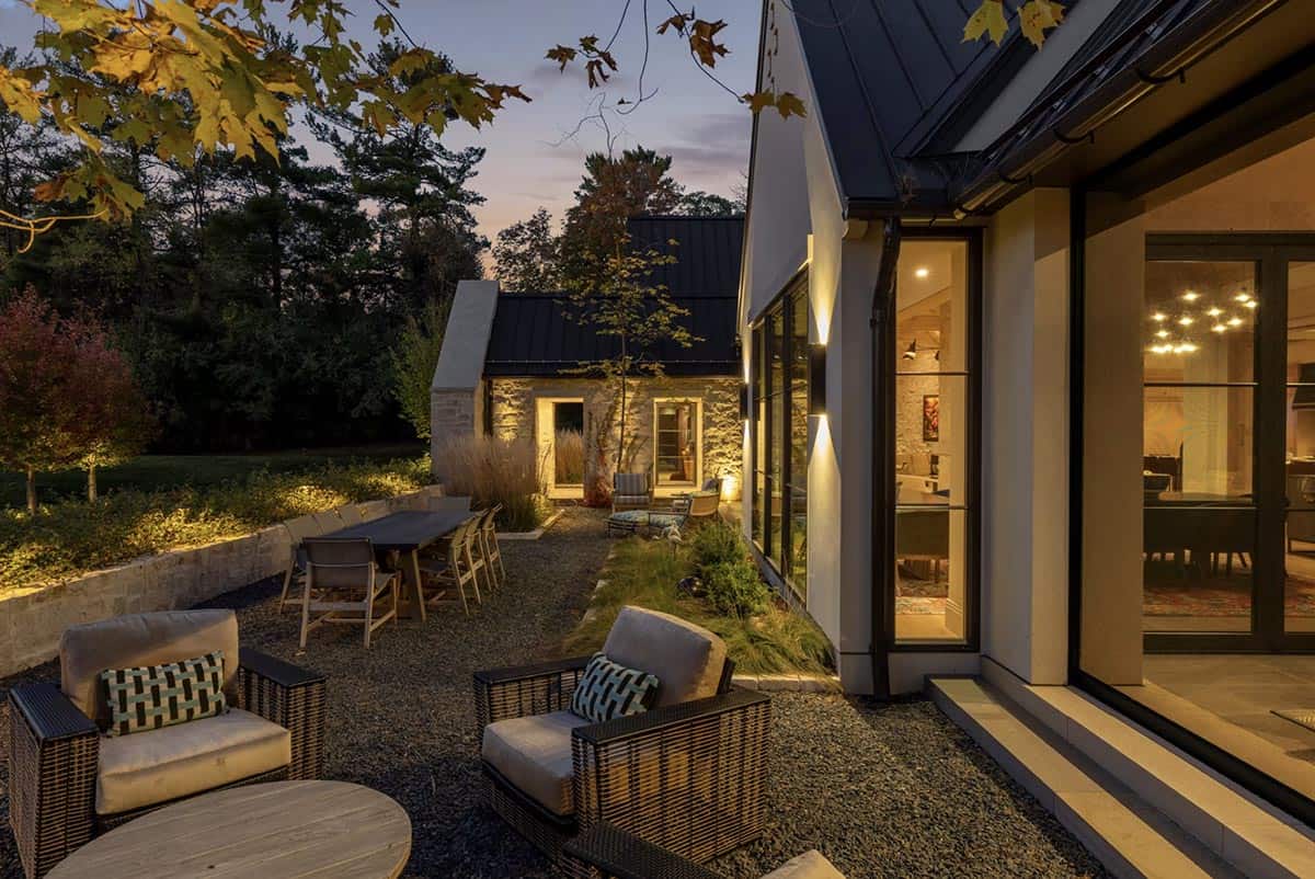 Dusk patio view with glowing dining room and stone facade