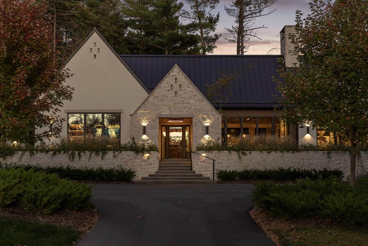Dusk view of the front entrance with stone gable and illuminated door