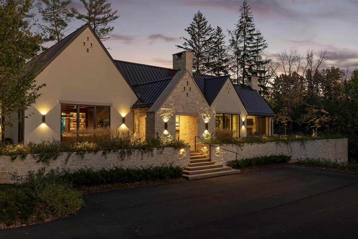 Dusk view of front stone entry with lit stair hall beyond