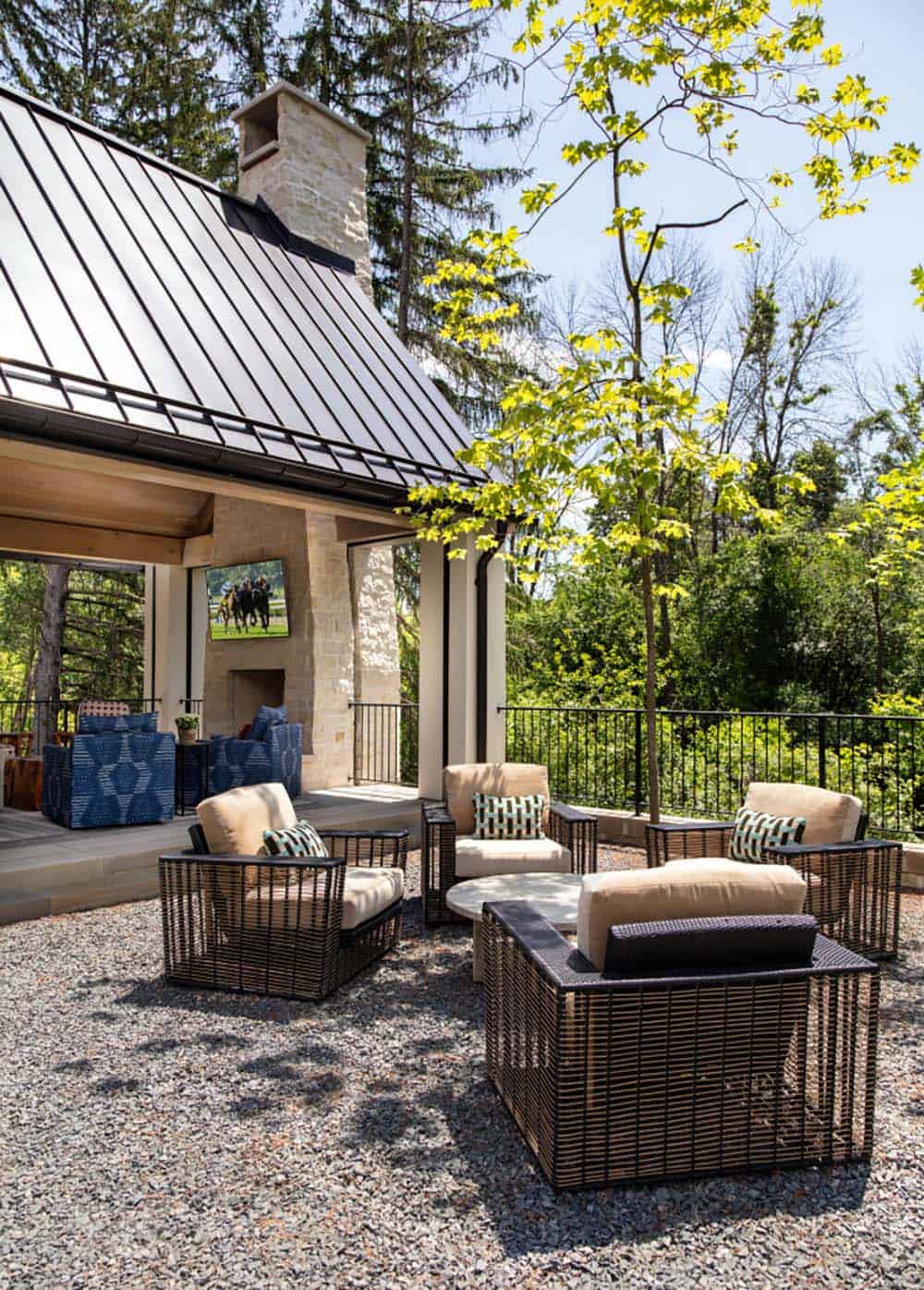 Gravel patio seating with stone chimney and covered porch beyond