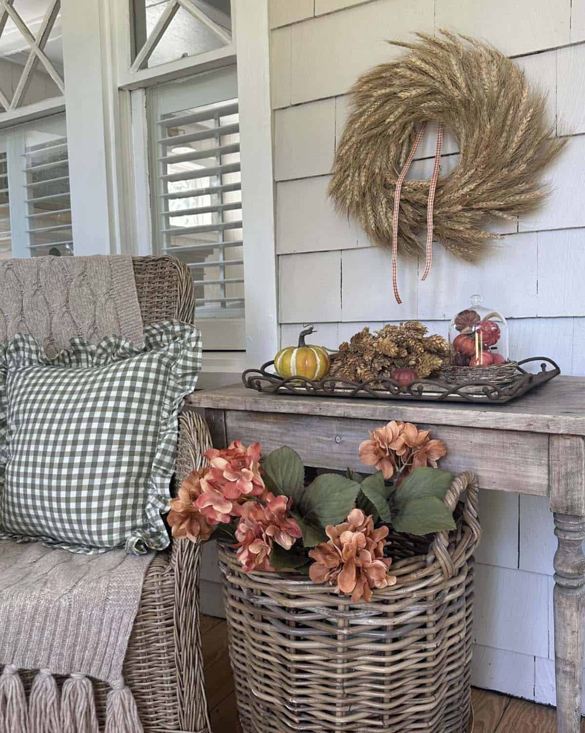 Scrolled metal tray with pumpkin, dried hydrangea, and glass cloche on porch console
