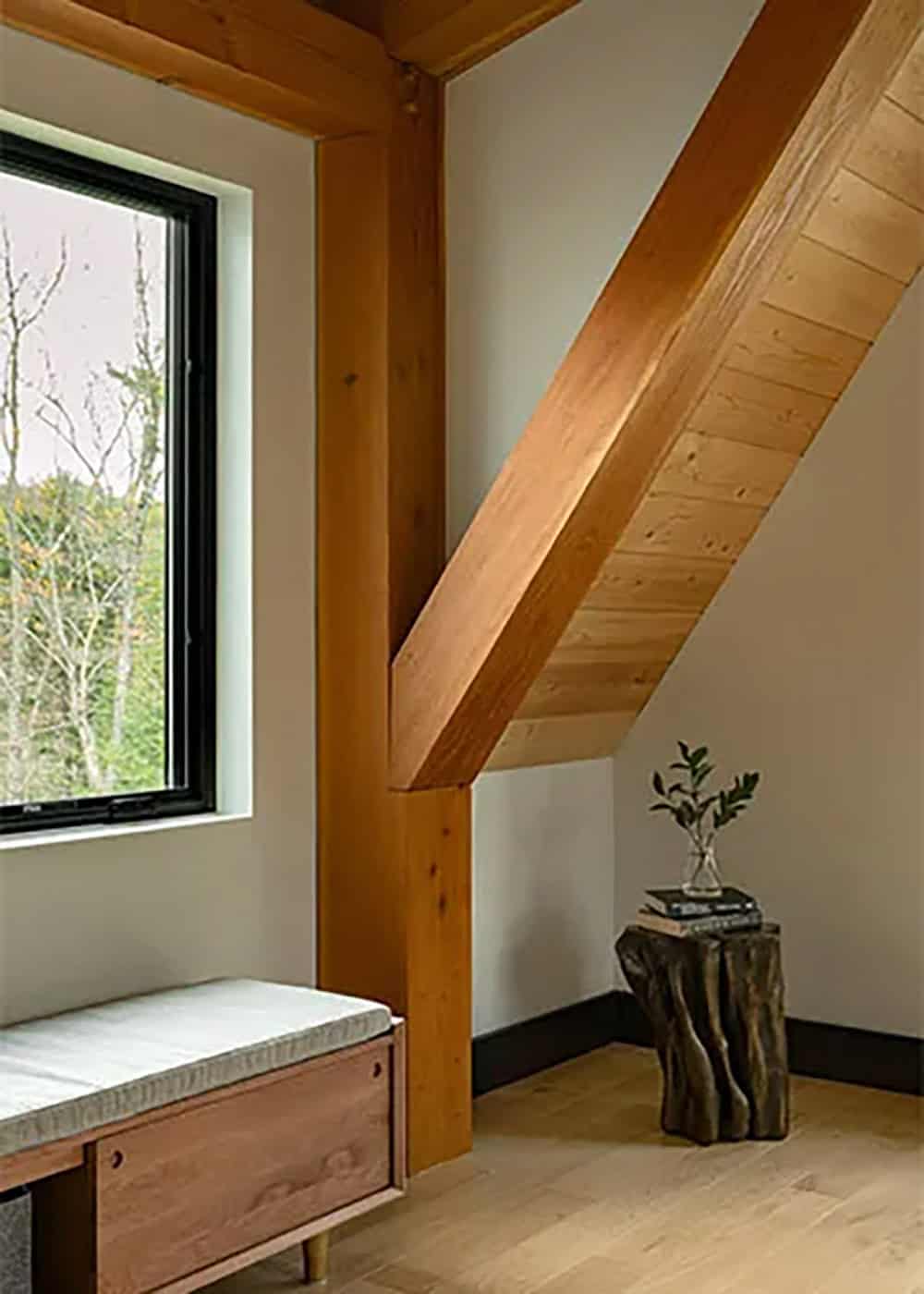 Bedroom corner with a timber post and diagonal brace, a cushioned storage bench and a tree stump side table