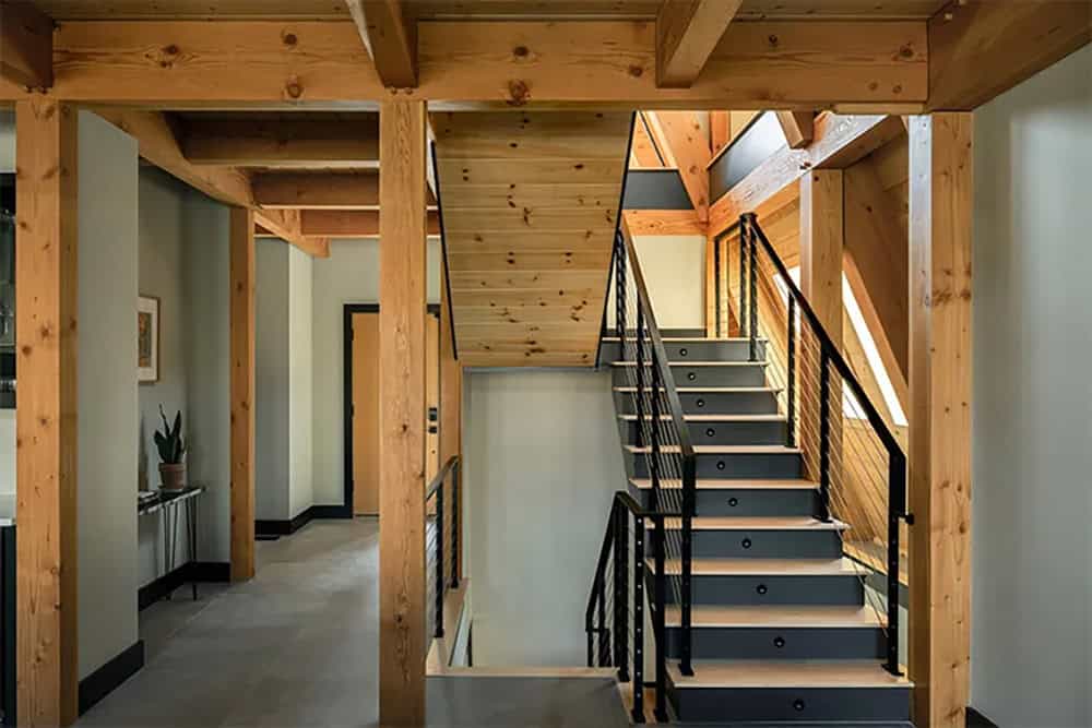 Entry hall with timber posts and beams, a gray tile floor and an open staircase leading up and down