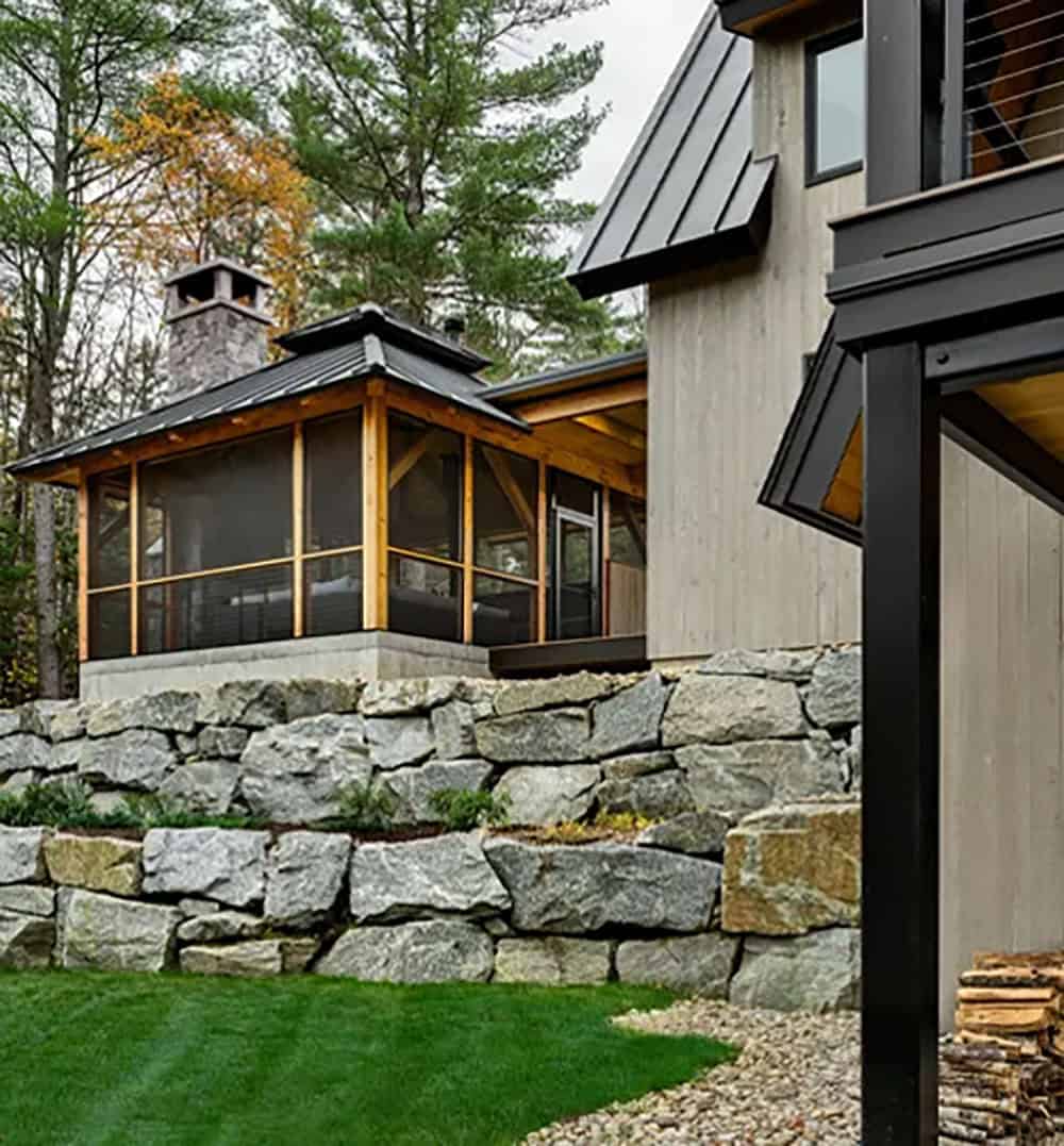 Screened porch with timber posts set on a concrete base above stacked granite boulder retaining walls