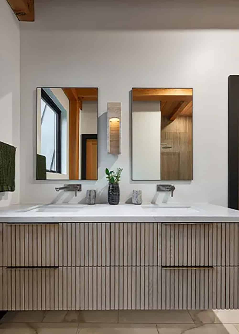 Double vanity with fluted wood drawers, a white countertop, wall-mounted faucets and two rectangular mirrors