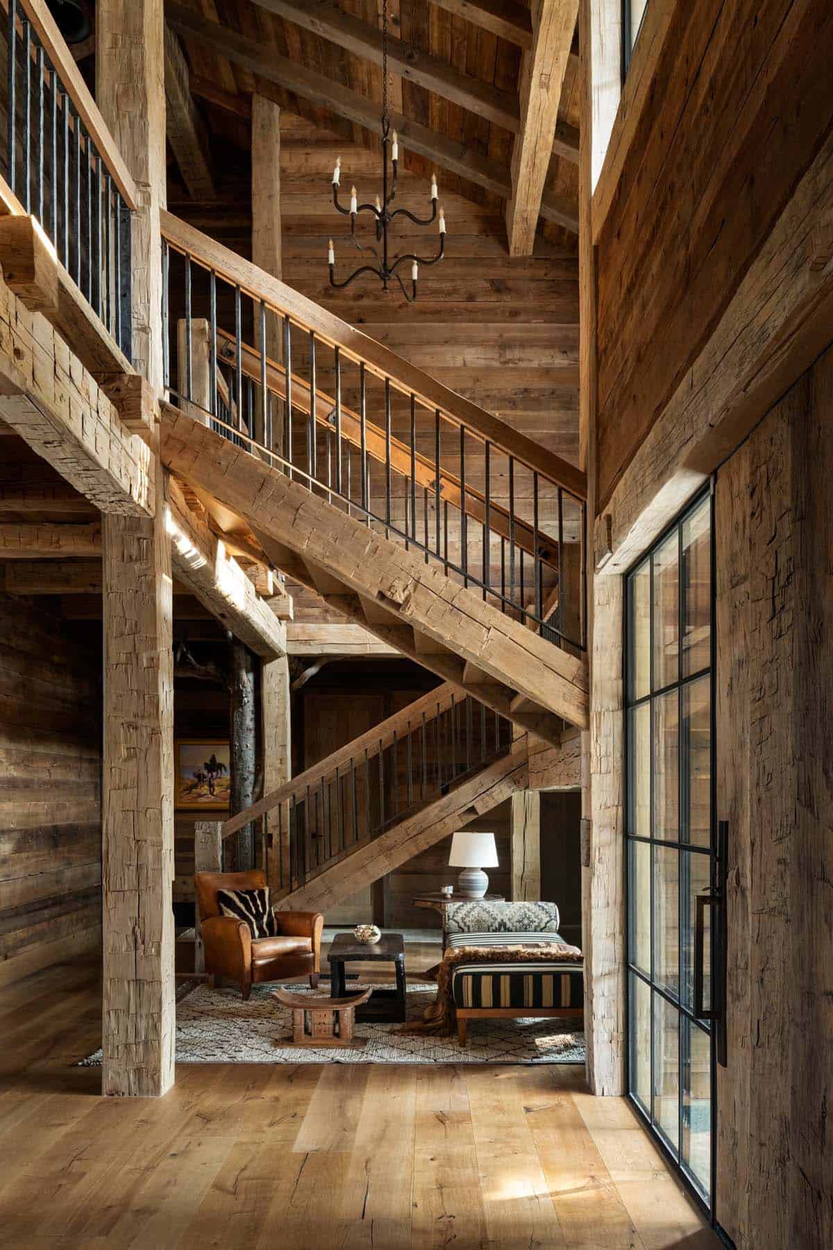Timber frame staircase with iron railing above a leather chair sitting nook