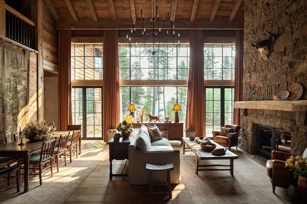Great room with two-story steel windows, rust curtains, and stone fireplace
