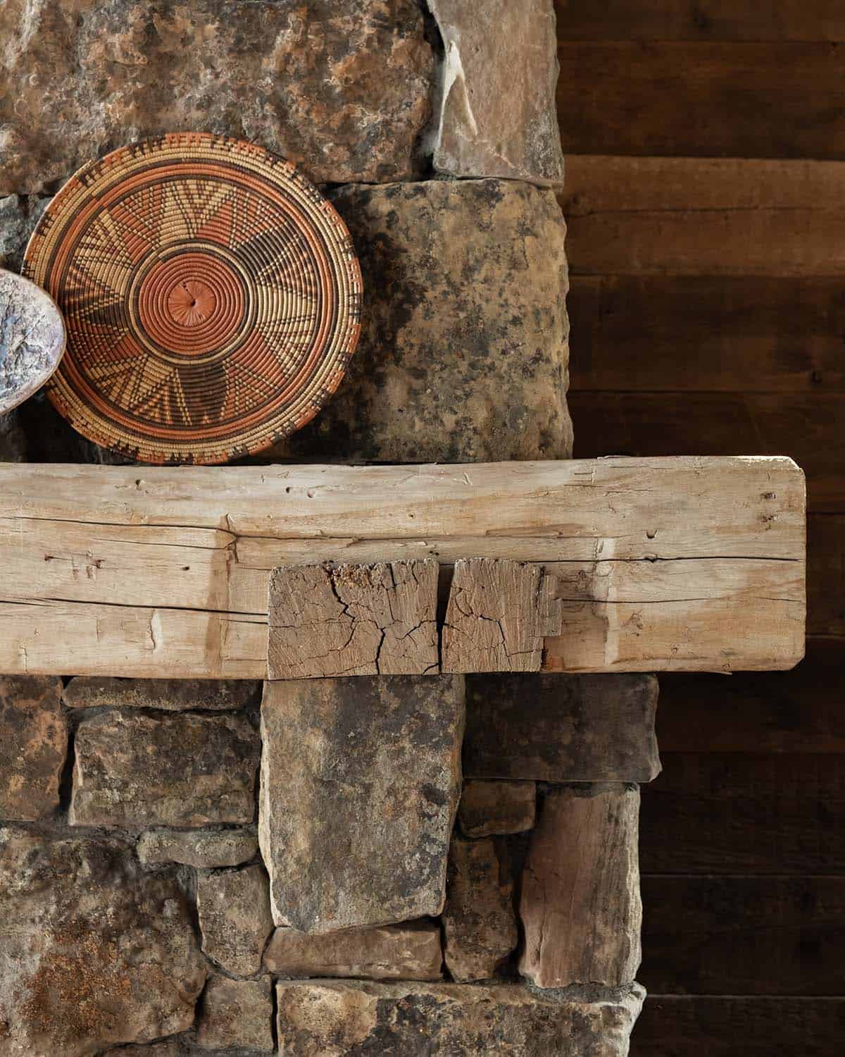 Hand-hewn wood mantel with a woven basket on a stone fireplace