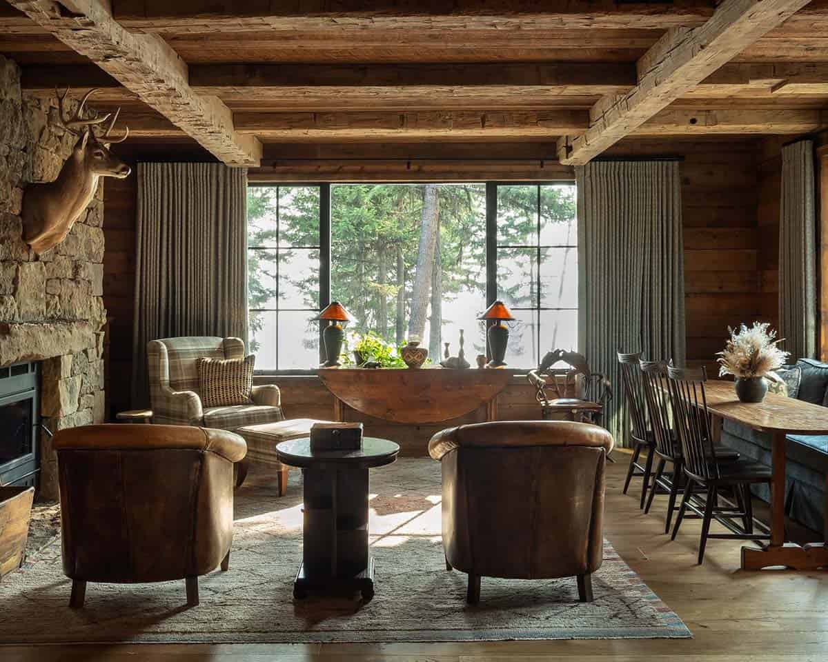 Den with stone fireplace, deer mount, and leather club chairs