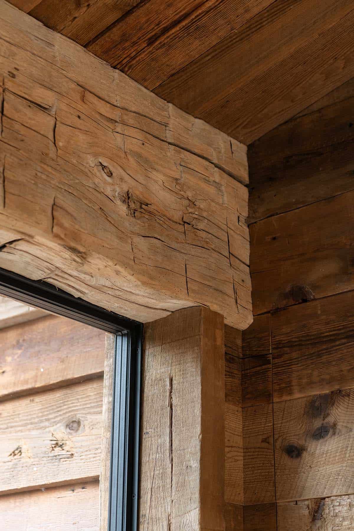 Close-up of a hand-hewn timber beam over a steel window