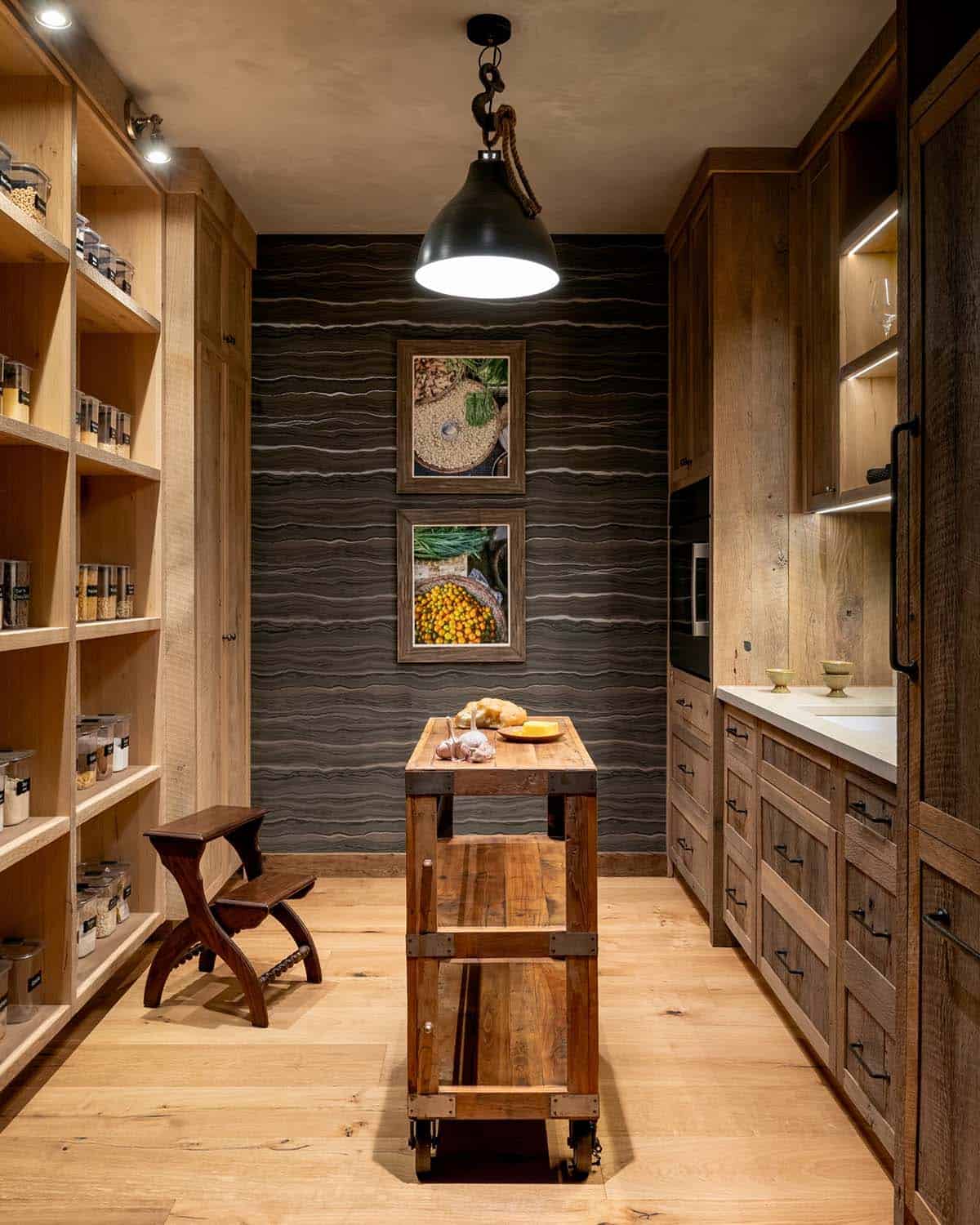 Walk-in pantry with open shelving, rolling cart, and black pendant