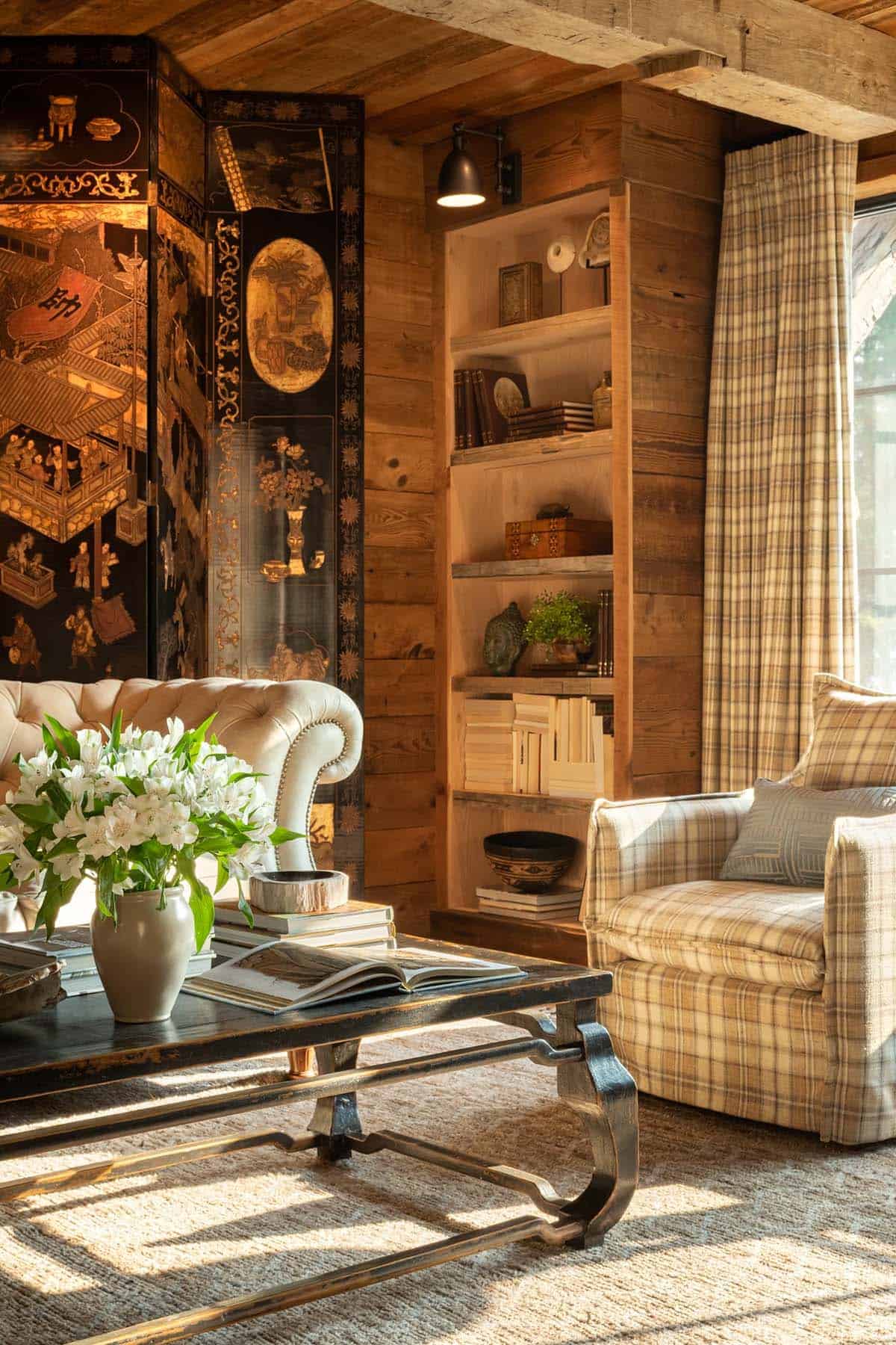 Built-in bookshelves beside a plaid armchair and lacquer screen