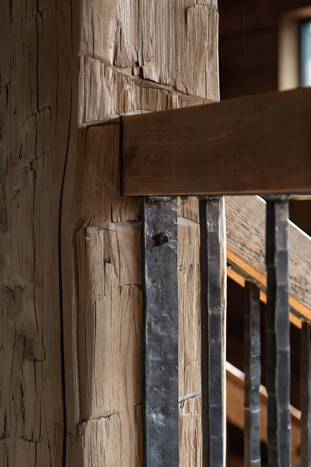 Hand-forged iron balusters against a hand-hewn timber post