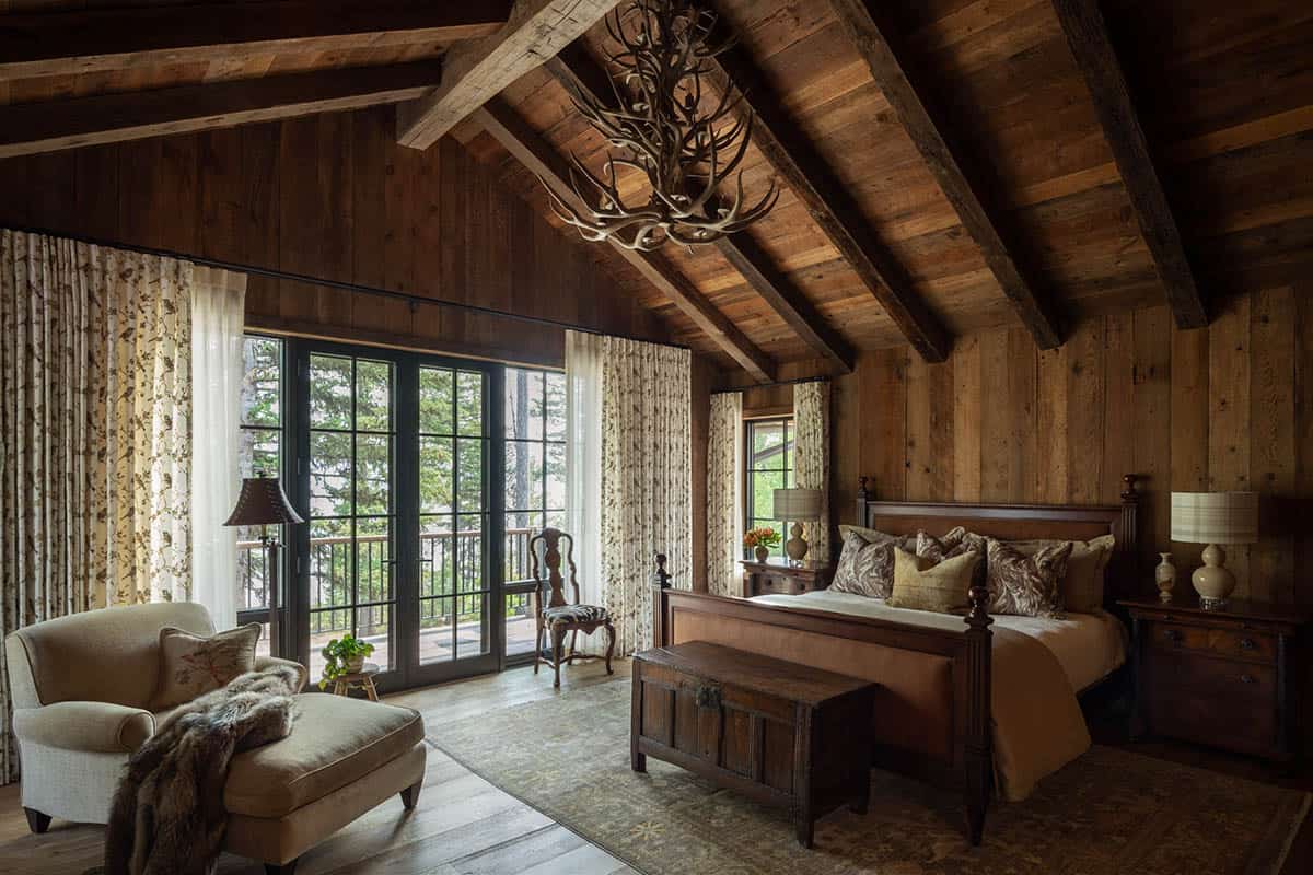 Primary bedroom with antler chandelier and French doors to a balcony