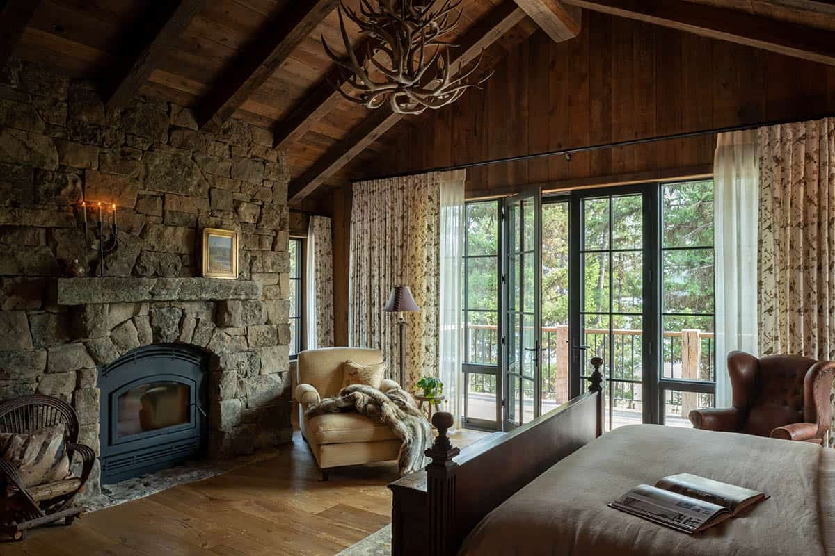 Primary bedroom with stone fireplace and cream chaise lounge