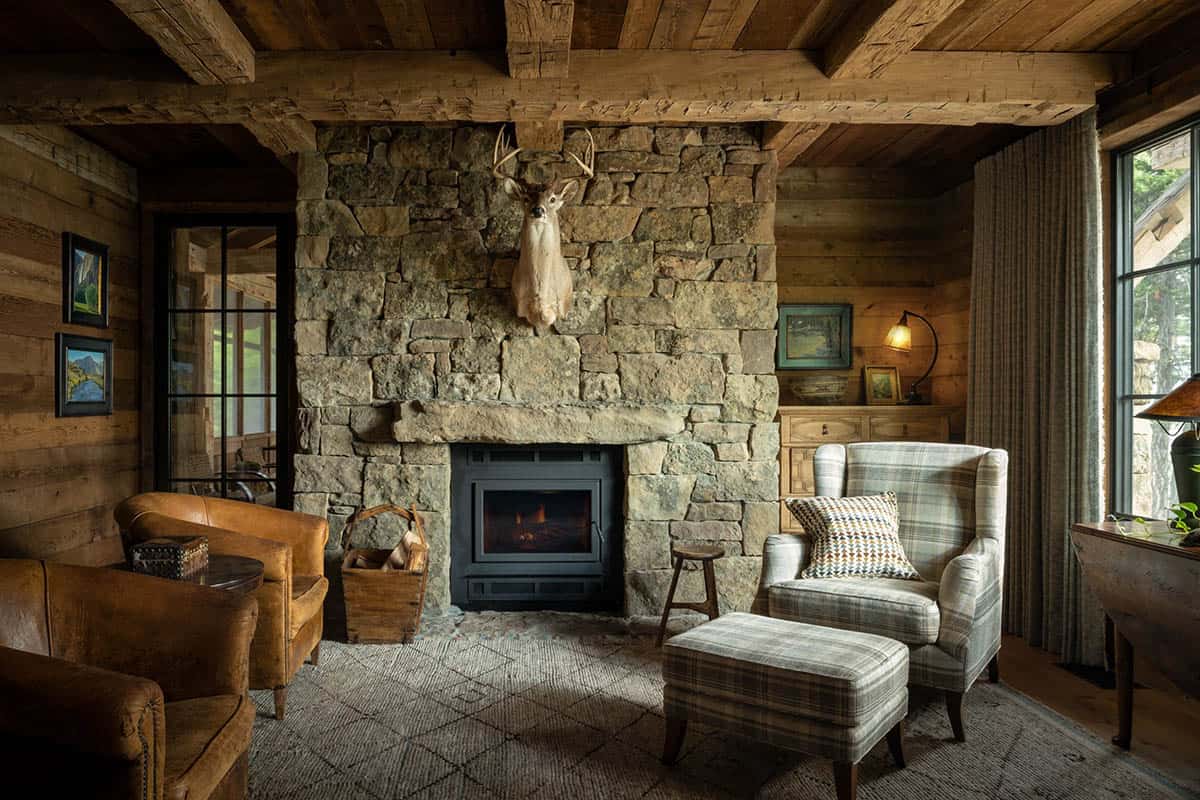 Den with stone fireplace, deer mount, and plaid wingback chair