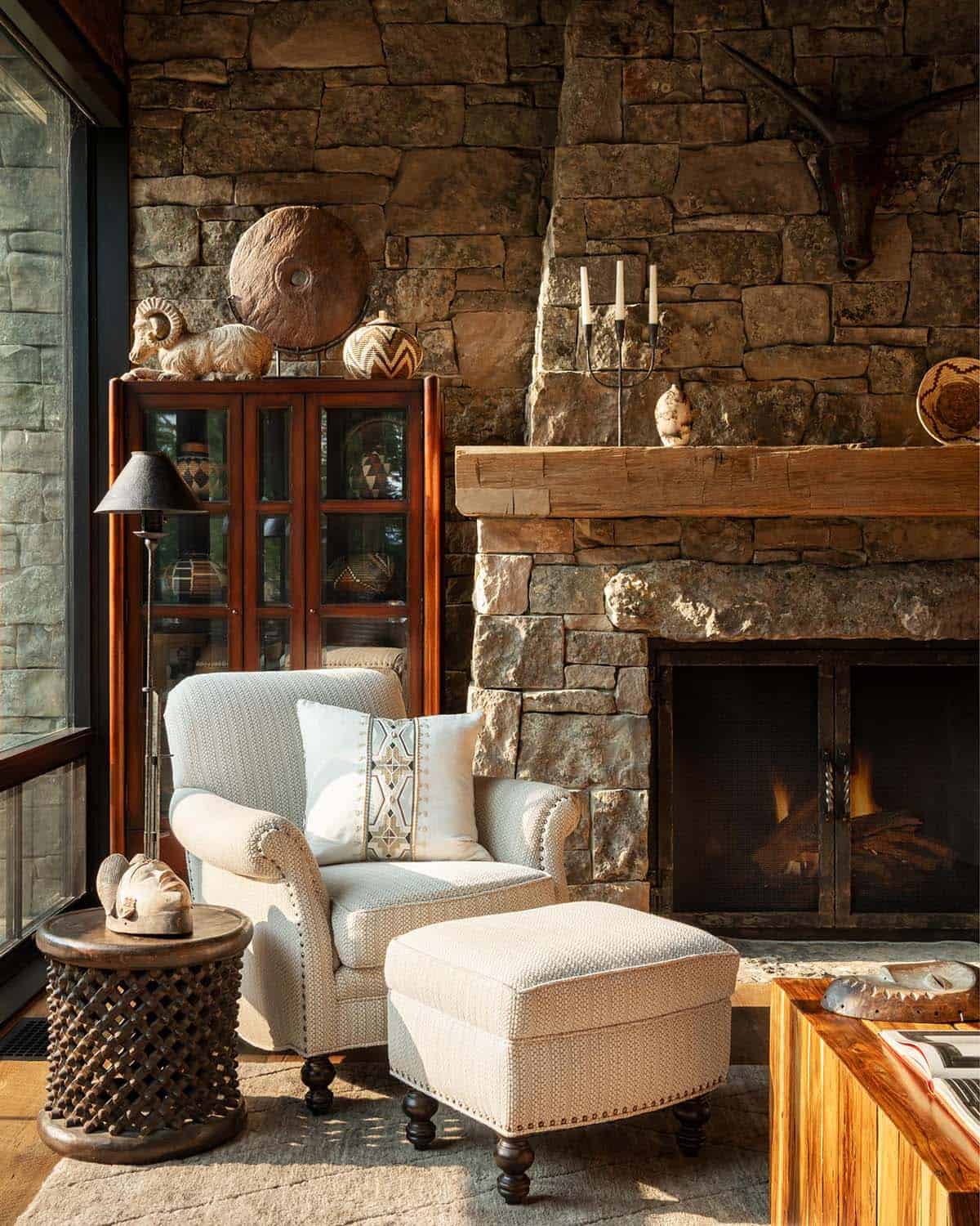 Cream armchair by a stone fireplace with a cabinet of woven baskets