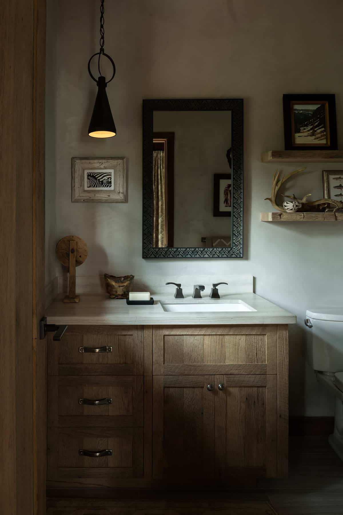 Bathroom with oak vanity, carved black mirror, and cone pendant