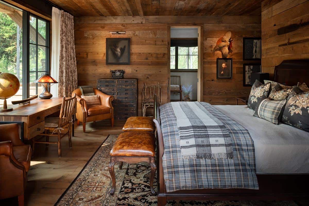Guest bedroom with plaid bedding, leather bench, and writing desk