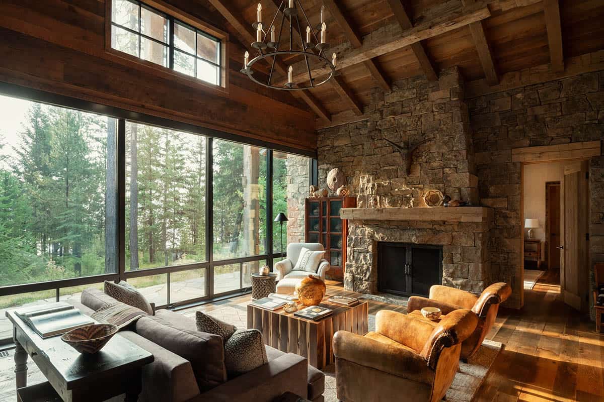 Guest cabin living room with glass walls and stone fireplace