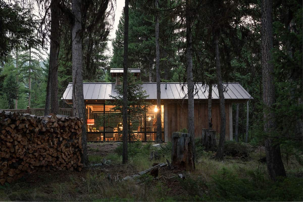 Artist studio glowing at dusk with stacked firewood