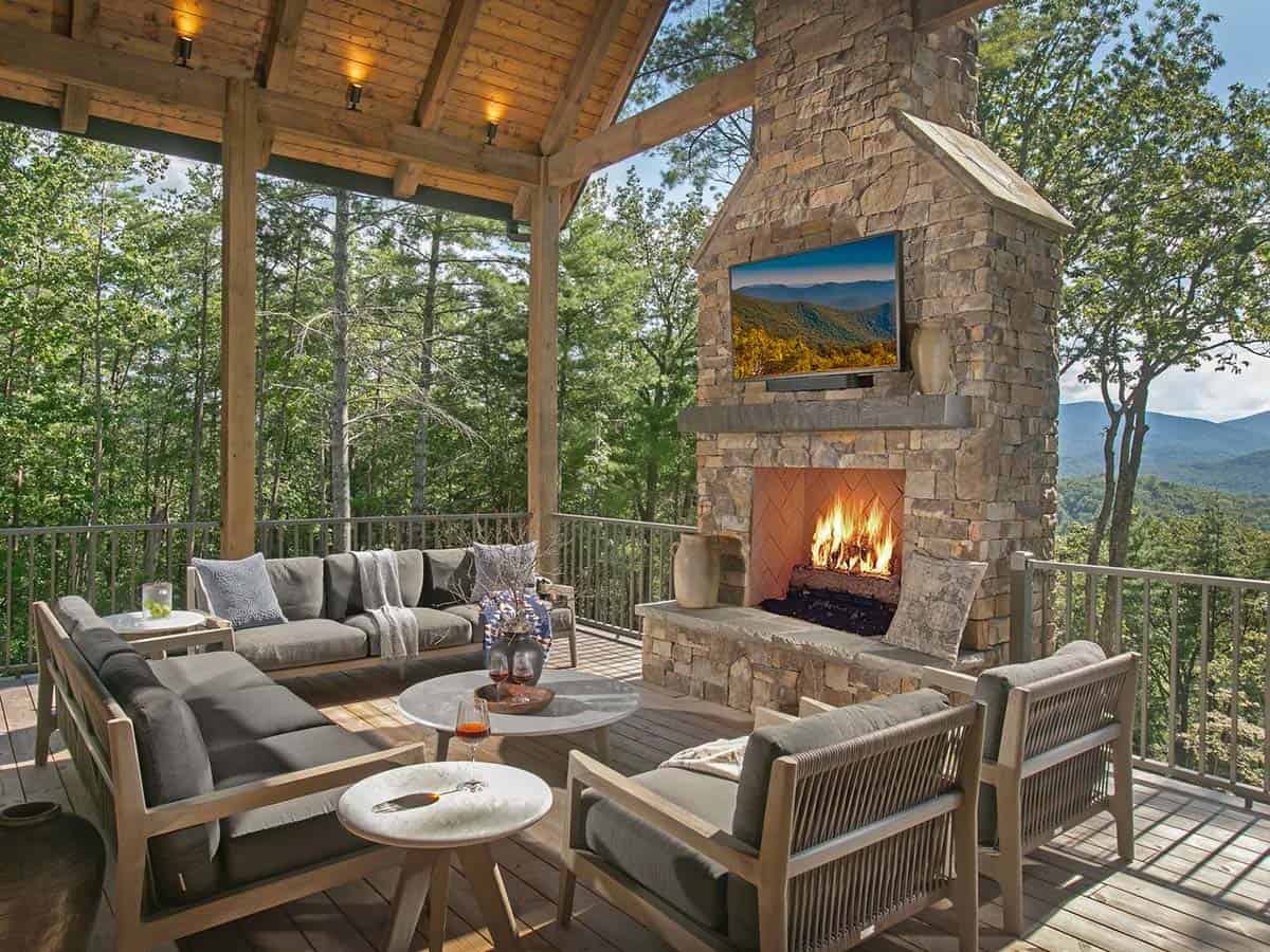 Covered living porch with stone fireplace, outdoor sofas and Blue Ridge Mountain views