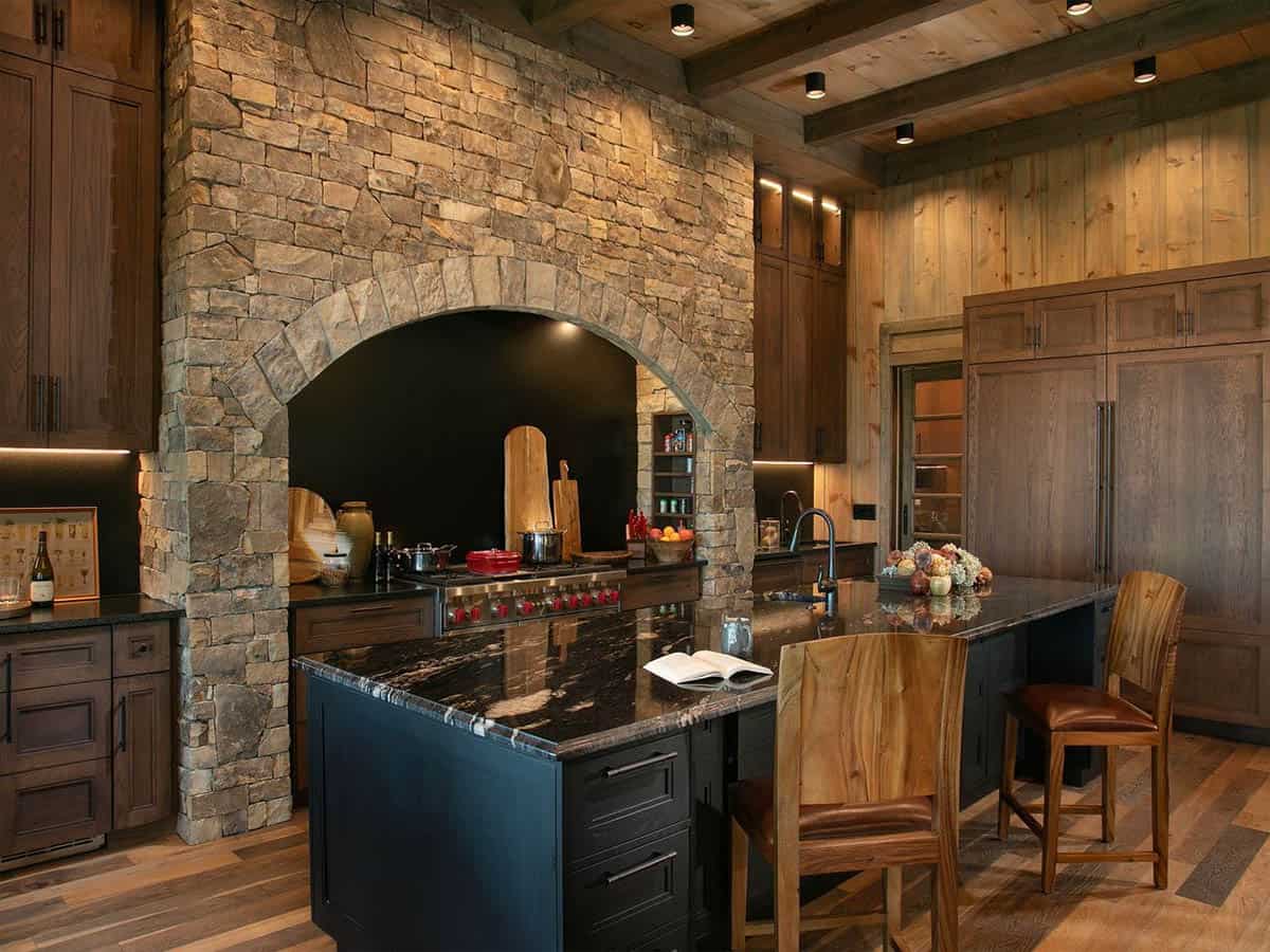Kitchen with arched stone stove surround and dark granite island