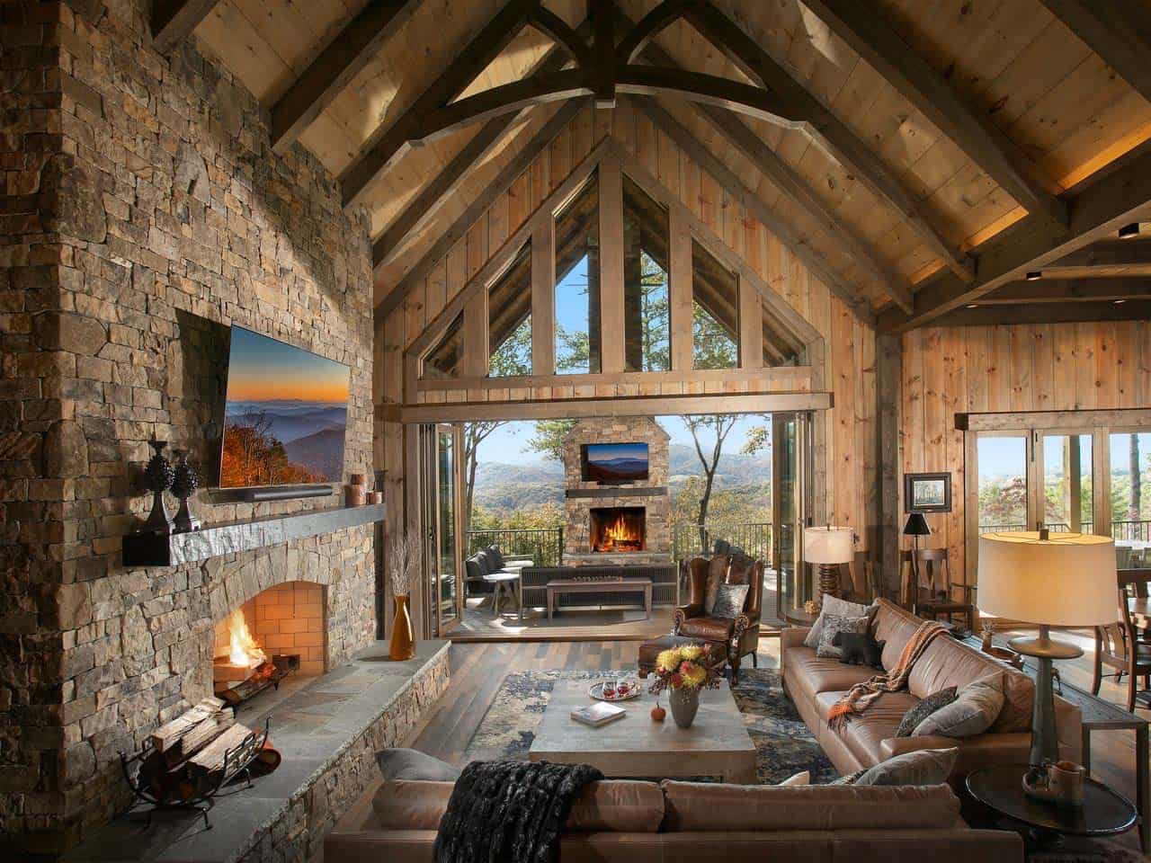 Great room with timber trusses, stone fireplace and folding doors to the porch