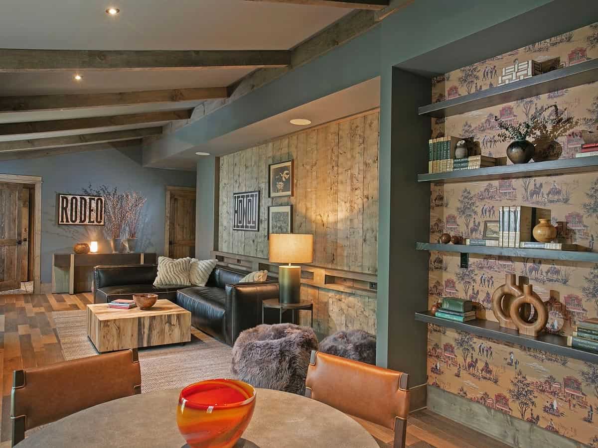 Lounge with black leather sofa and shelves backed by western toile wallpaper