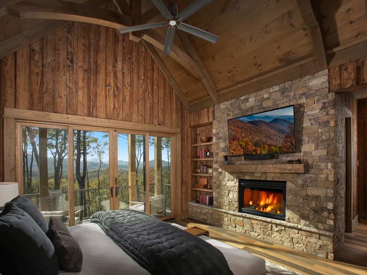 Primary bedroom with stone fireplace and sliding doors to a mountain view porch