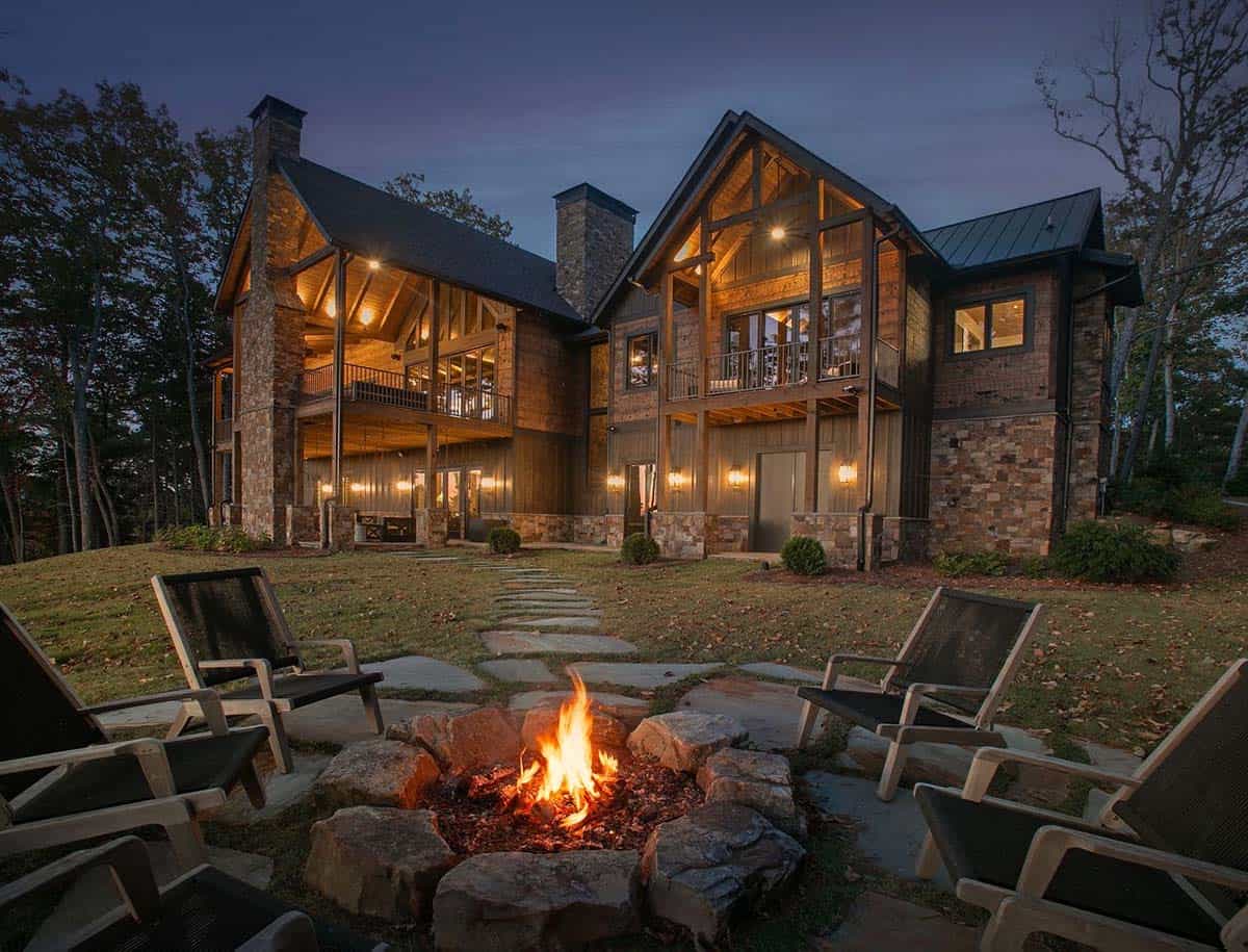 Back of the lodge at dusk with stone firepit and chairs in the yard