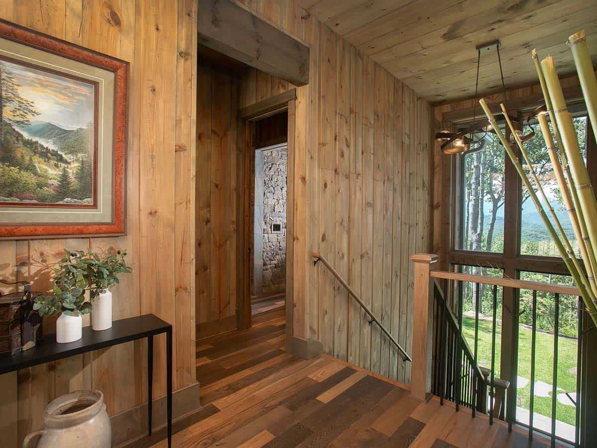 Stair landing with wood paneled walls and windows to the trees