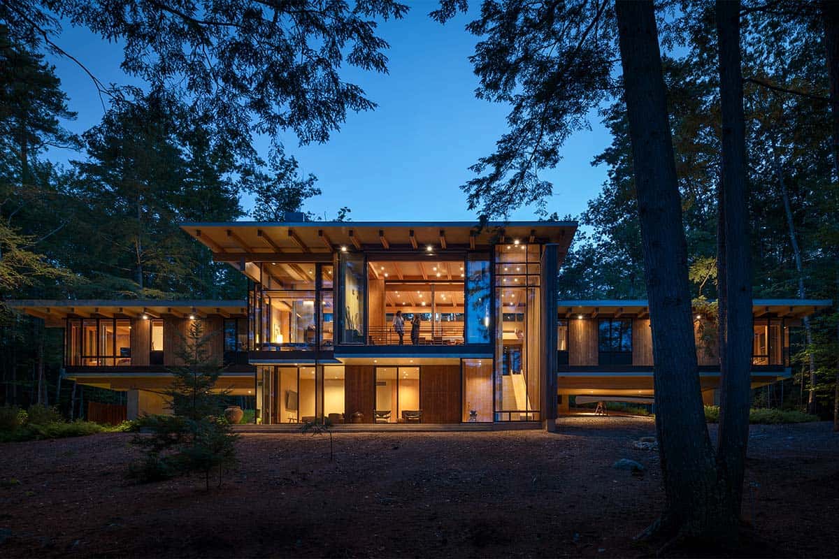 Lake house at dusk with glowing windows under a wide roof overhang