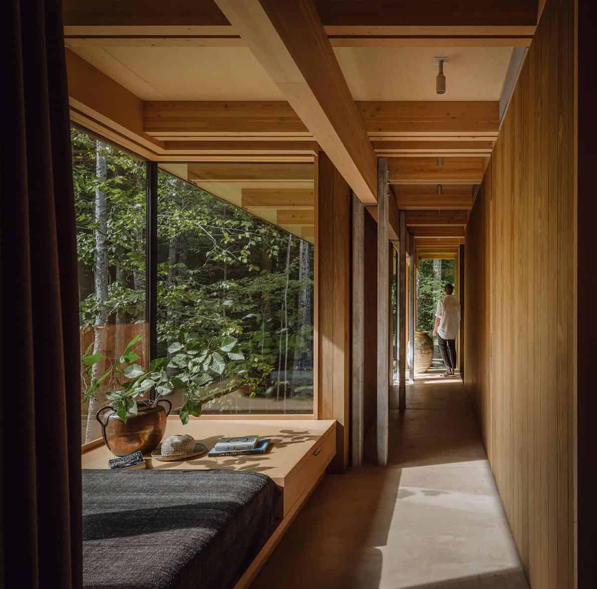 Hallway with a window seat daybed, wood walls, and a large clay urn at the far end