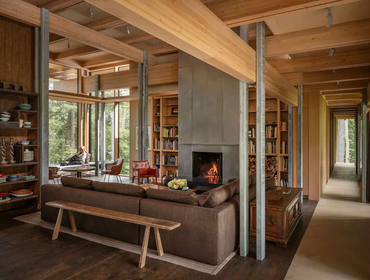 Living room with a brown sectional, steel fireplace, and a hallway along the right