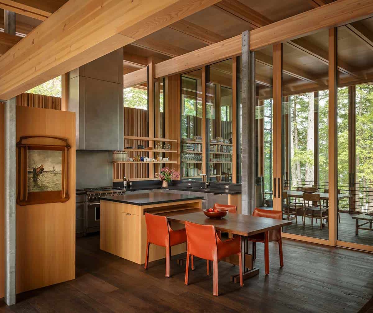 Kitchen with a steel range hood, wood island, and orange leather dining chairs