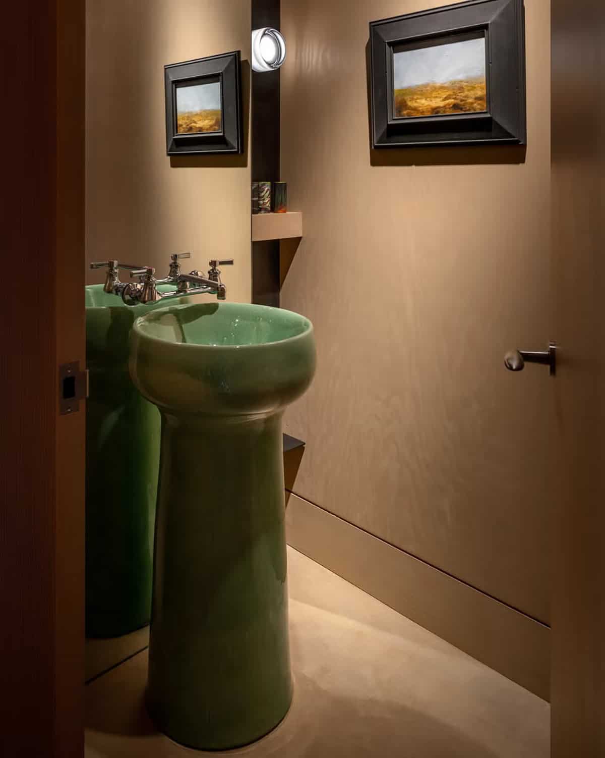 Powder room with a green ceramic pedestal sink and two small landscape paintings