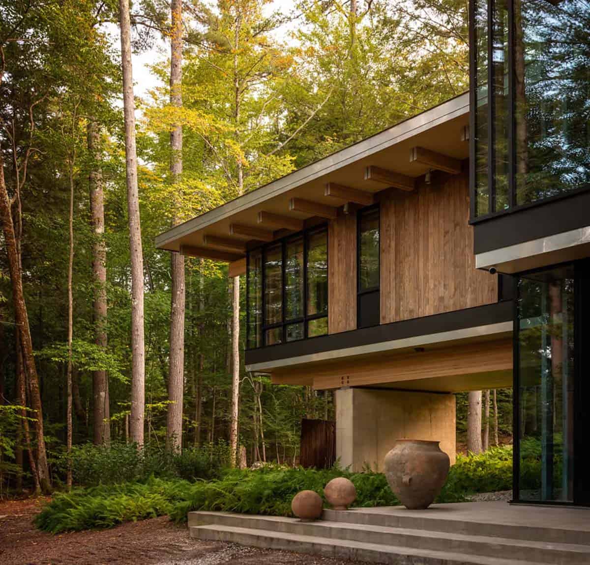 Cantilevered wing with wood siding above a concrete base and clay urns on the steps