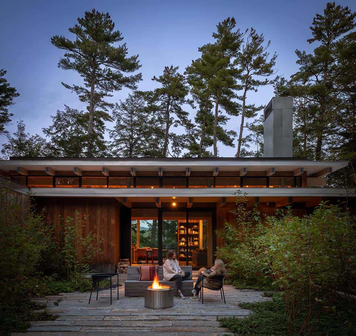 Stone courtyard with a fire pit in front of the lake house entry at dusk