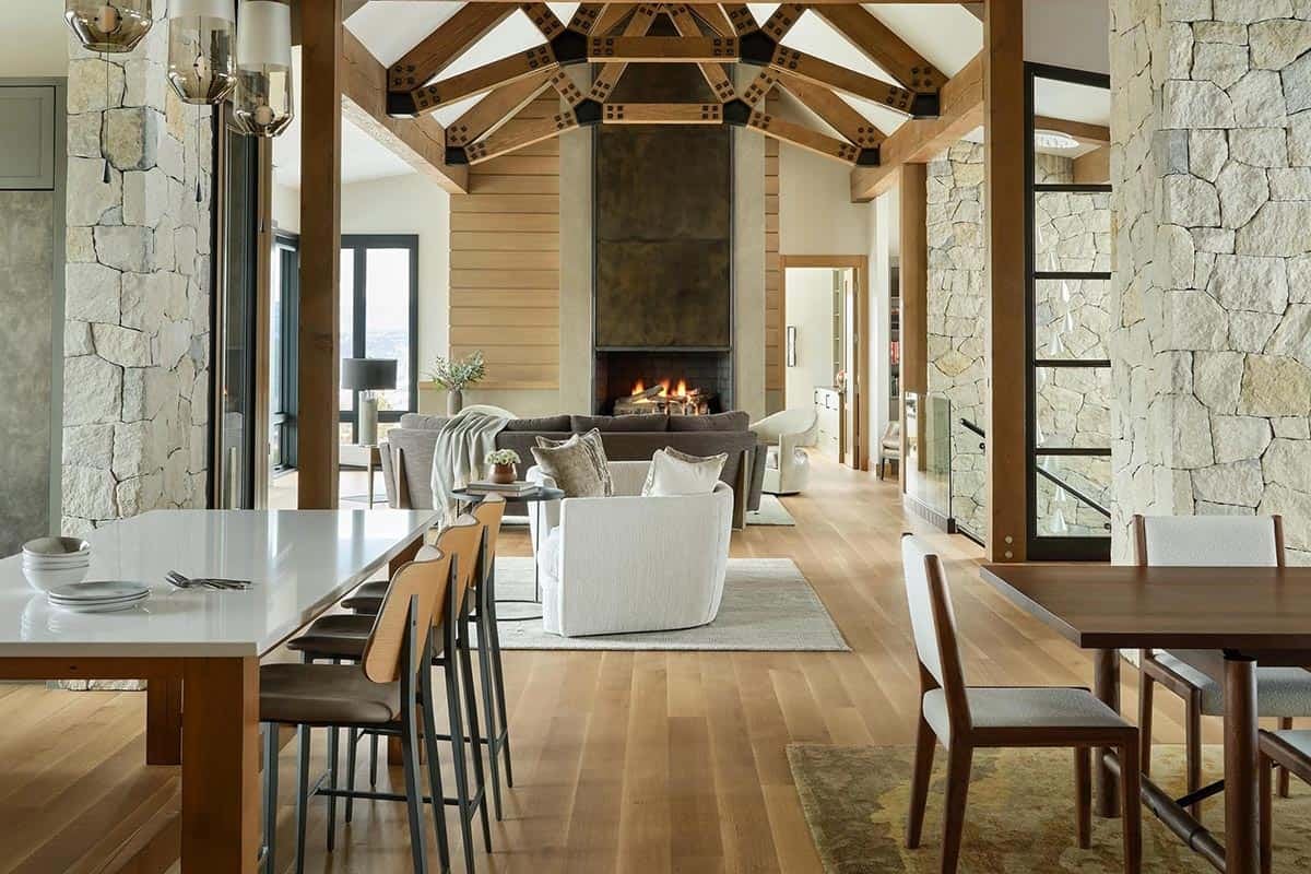 Great room with timber trusses and a steel-clad fireplace beyond the kitchen island