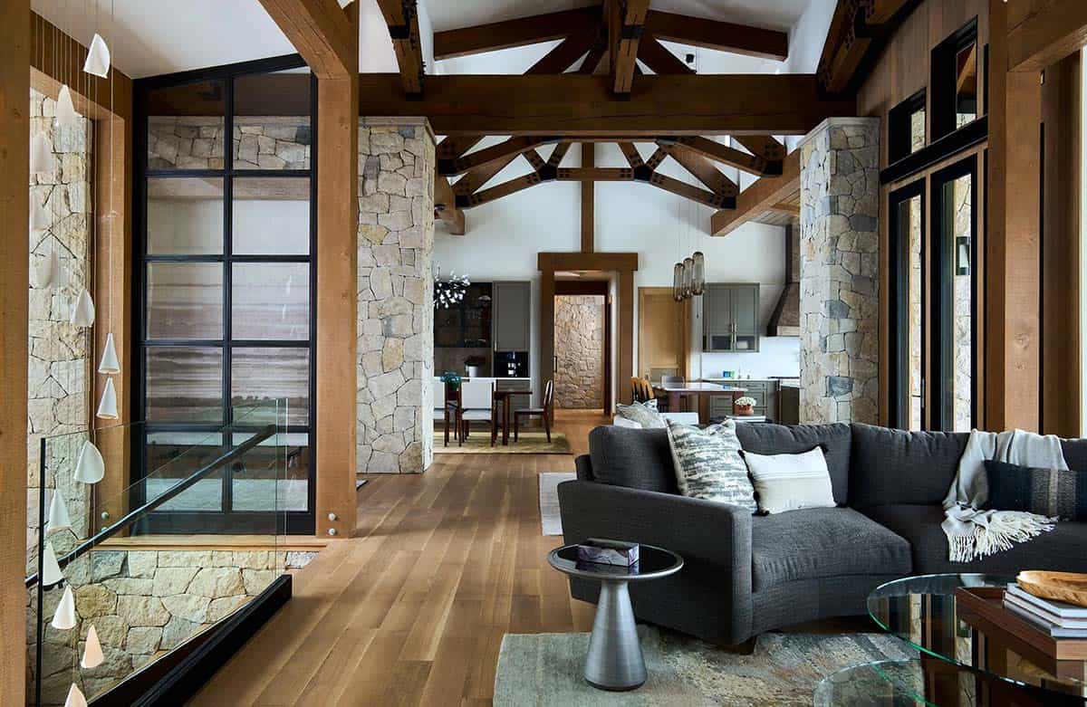 Great room with timber trusses, stone columns, and a charcoal sofa