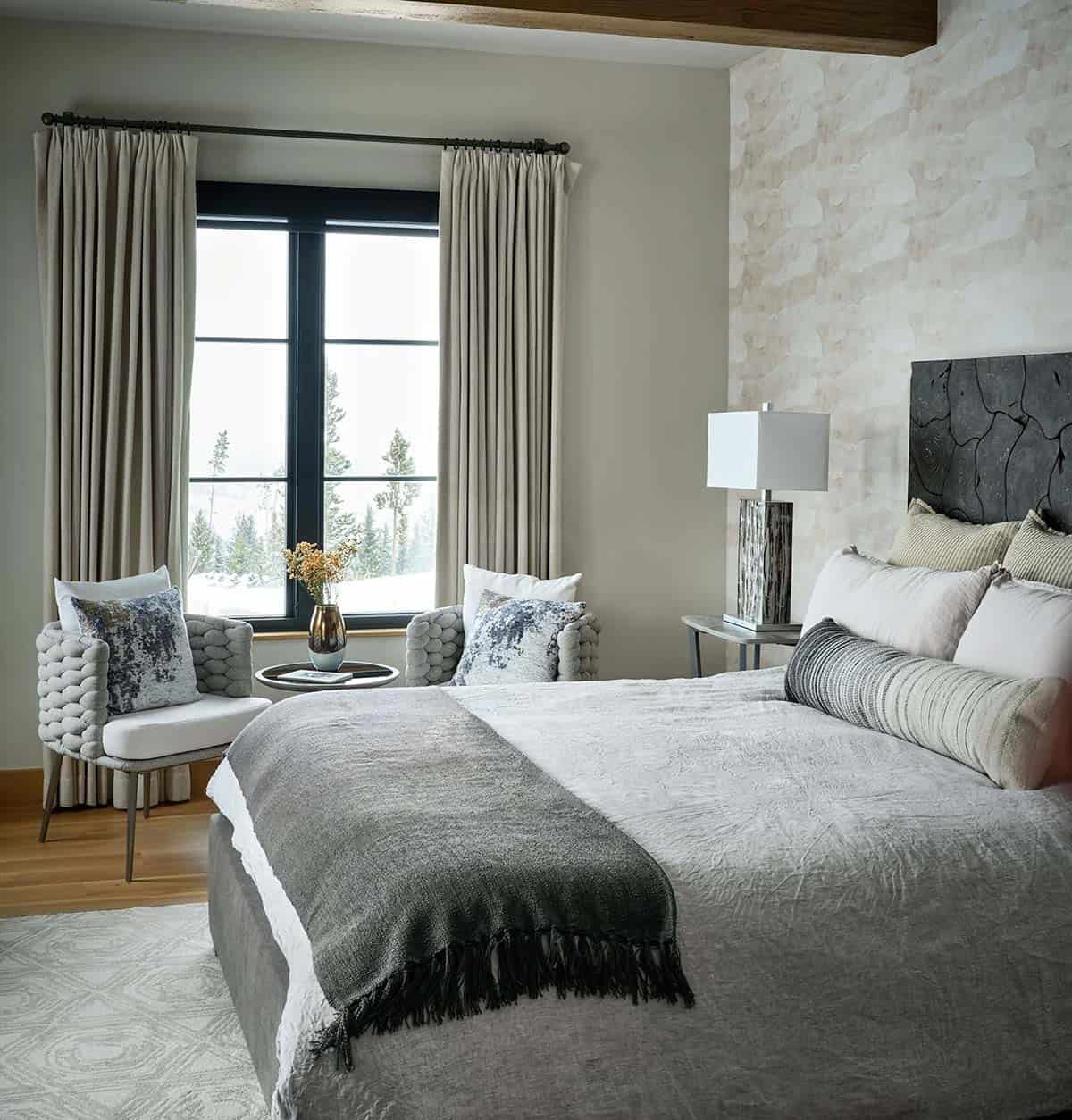Guest bedroom with carved wood headboard and woven armchairs