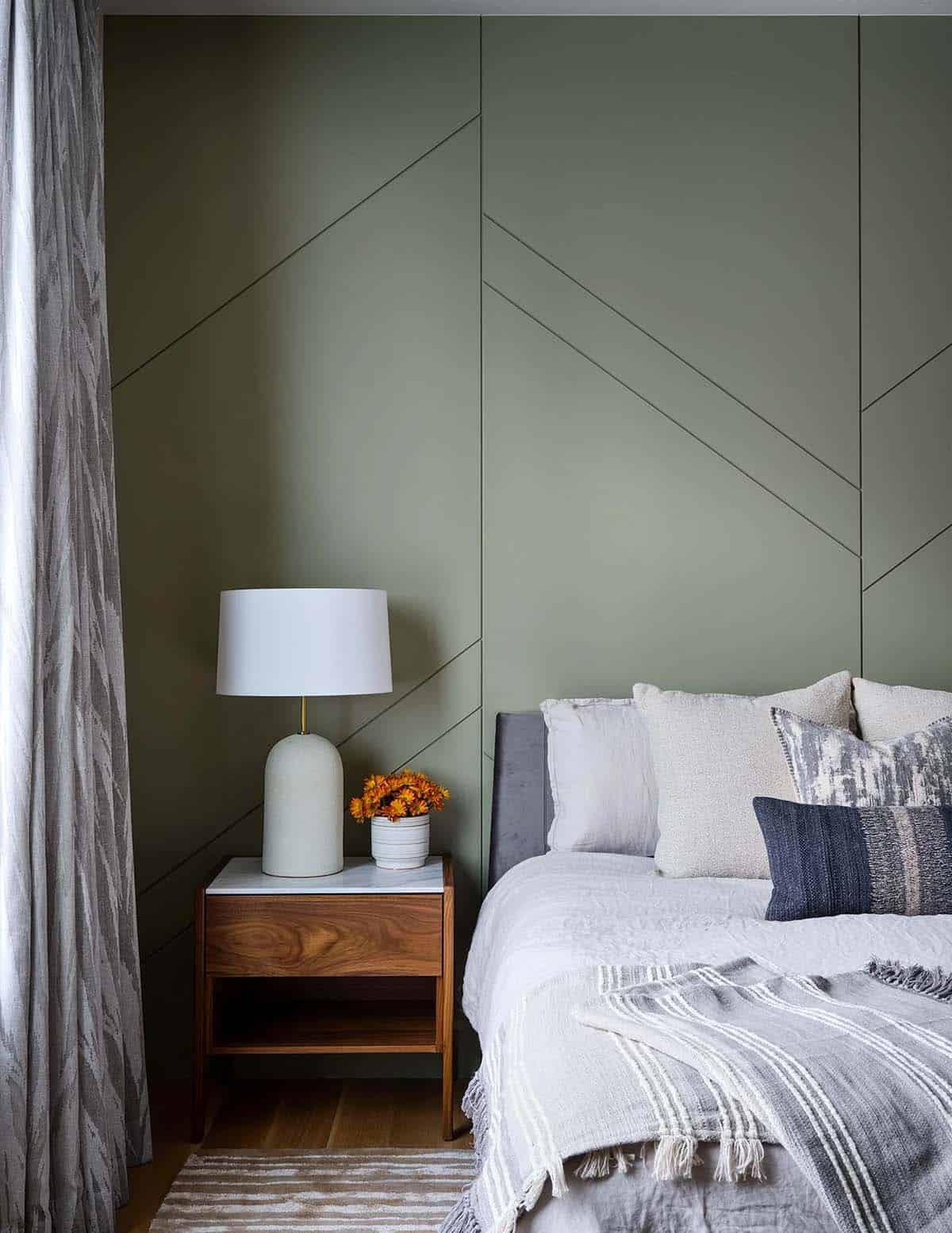 Guest bedroom with sage green geometric paneled wall and walnut nightstand