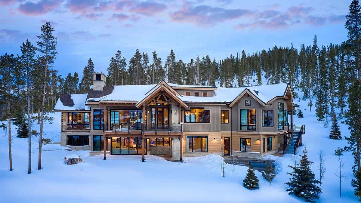Rear of the mountain home at dusk with lit windows and a deck